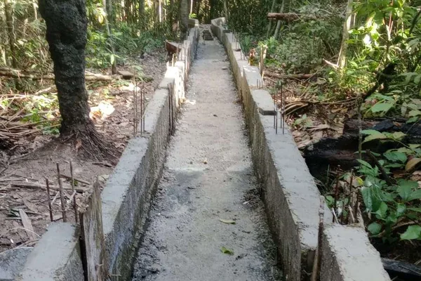 Canaleta de drenagem pluvial concluída, concretada em linha dentro da mata